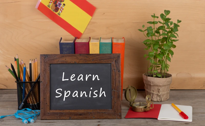 Learn Spanish chalkboard with Spanish flag nearby.